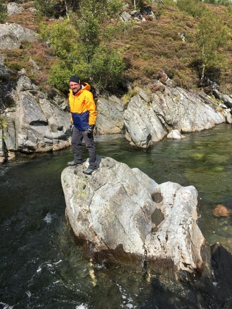 The blog author, standing on a rock on a river in the sunshine