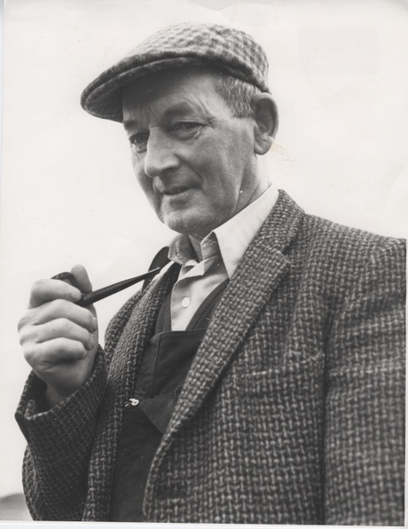Black and white photo of an older man smoking a pipe.