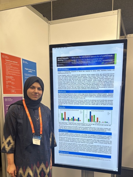 Asmaa stood next to a screen showing her research poster
