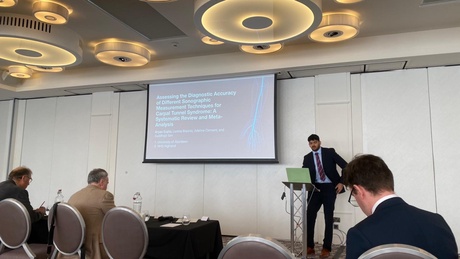 A man stood presenting to a room of people