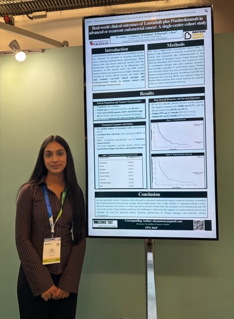 Miya stood next to a screen showing her research poster