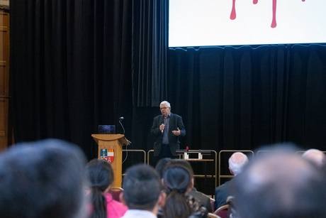 A man on stage speaking to an audience