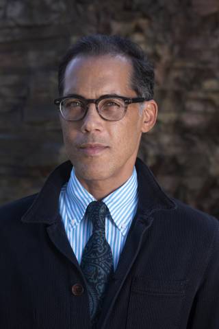 A headshot photograph of a smartly dressed Matthew Smith outside