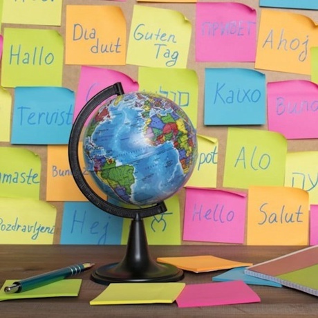 A globe on a desk with the background covered in post-its that say 'hello' in different languages
