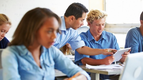 Secondary teacher helping secondary students in classroom setting