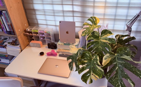 Image of desk with items on it such as alarm clock and laptop