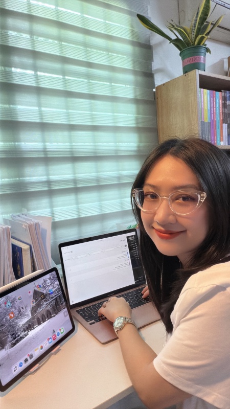 Ngoc Buu Ly smiling at camera with laptop and plants on desk in the background