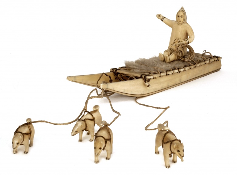 Inuit carving of a hunter travelling on a sled pulled by huskies, carrying hunting equipment ABDUA:85006