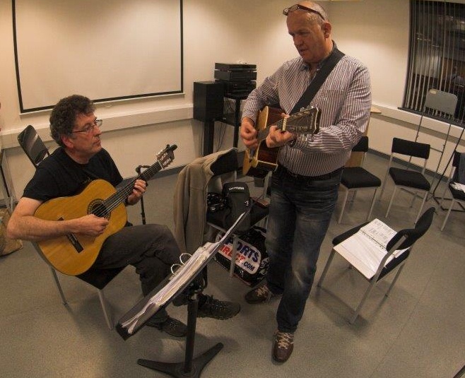 Two guitar players tuning