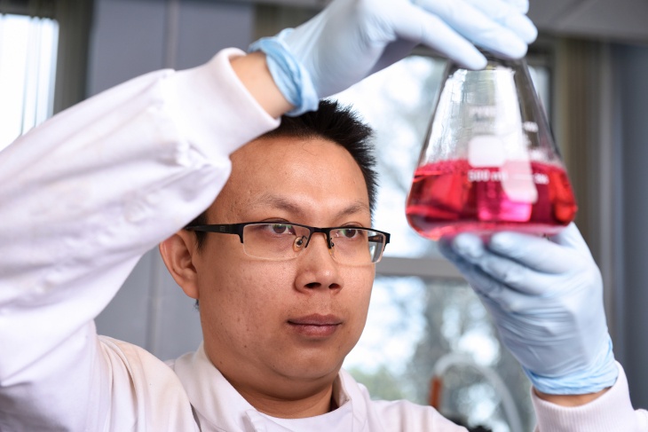 Researcher holding a beaker of red liquid