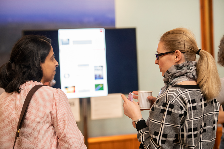 women networking at the symposium and looking at posters on screen