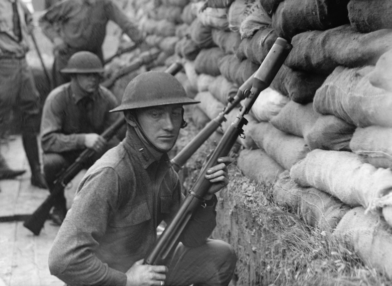 A soldier standing in a trench all in black and white