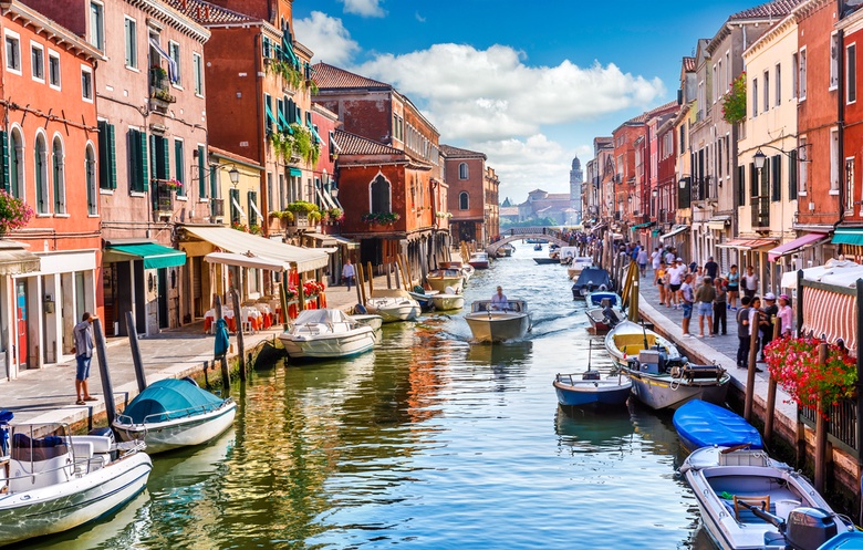 Colourful houses lining a canal in venice as boats drift down the water