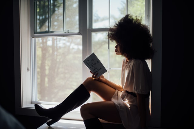silhouette of woman reading in window pane