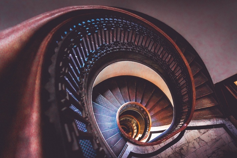 Image shows a dramatic spiral staircase made out of dark wood.