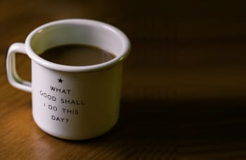 white and black ceramic cup filled with brown liquid on brown wooden sufface