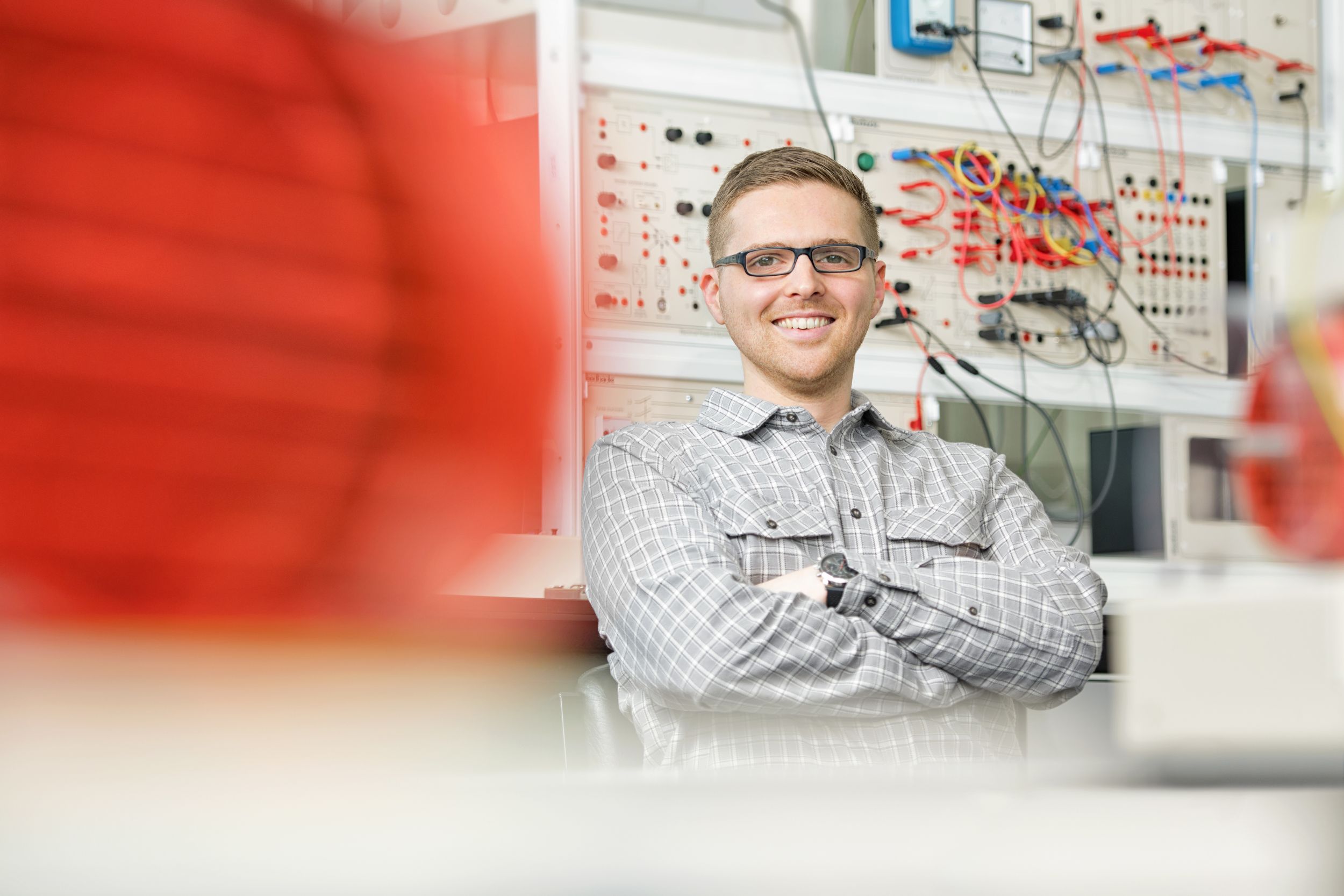 Photo of James Short sitting in a laboratory showing lab equipment in the background.
