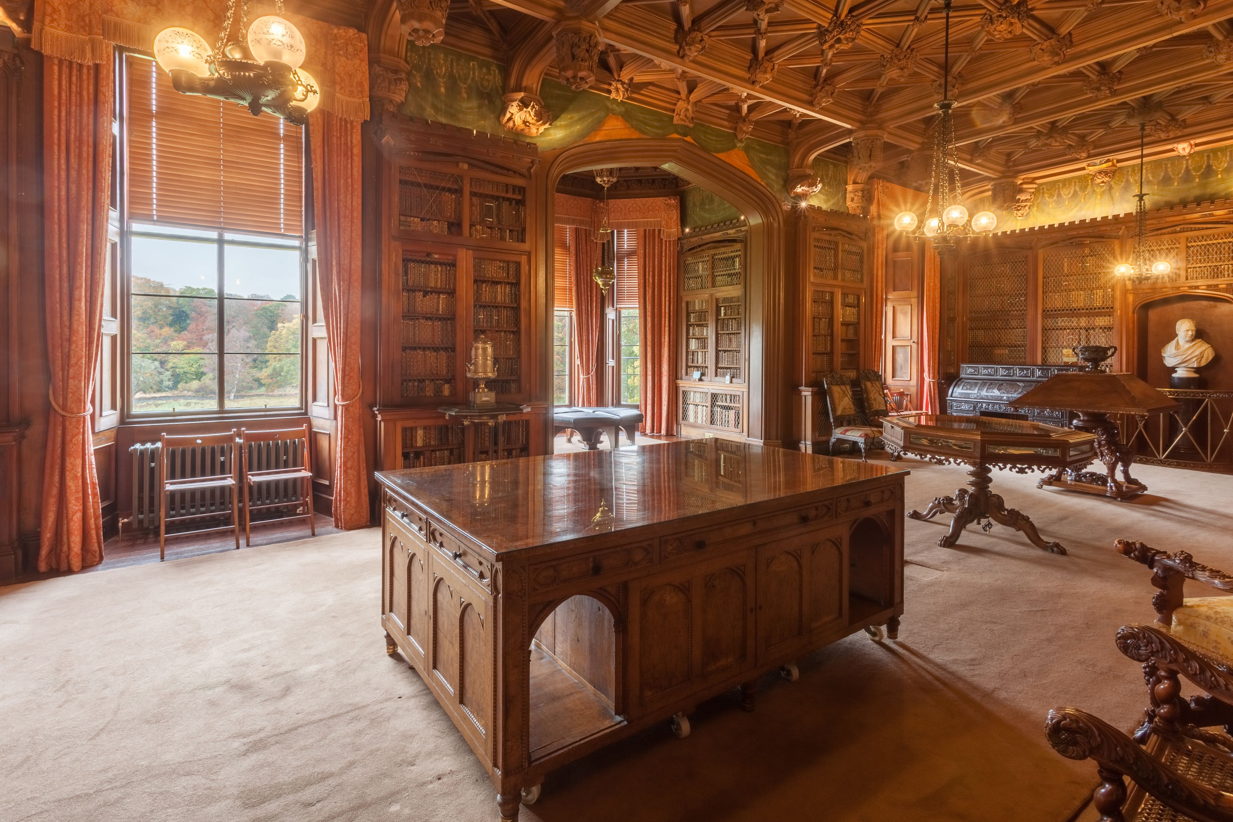 The library in Scott’s home, Abbotsford: a large, book-lined room with windows through which trees can be seen.